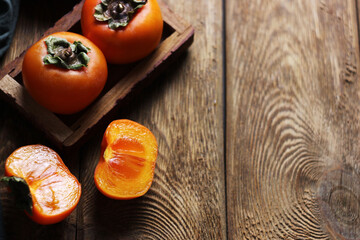 several ripe persimmons lie on a wooden table