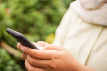 Selective focus on woman checking smartphone outdoors, representing social media, mobile activity, or digital lifestyle.