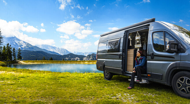 Frau mit ihrem Camper Van an einem Bergsee 