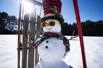 Obraz premium Snow man with festive decorations. Snowman in wintry backyard. Funny snowman with joyful expression outdoors. Snowman with scarf and hat for winter banner. Snowman in winter scene.