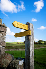 Wooden post with yellow arrow showing direction for footpath