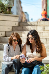 Mother and daughter using their cell phones outdoors