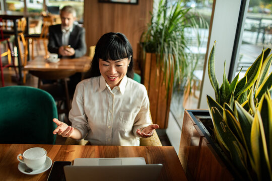 Adult woman smiling during online meeting at coffee shop