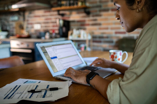 Adult woman focused on laptop work at home kitchen table