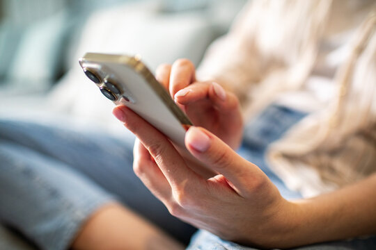 Focused adult using smartphone on couch at home - Powered by Adobe