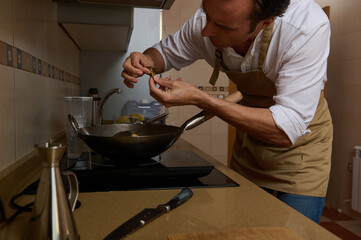 Chef In Apron Carefully Preparing Meal In Modern Kitchen For Dinner