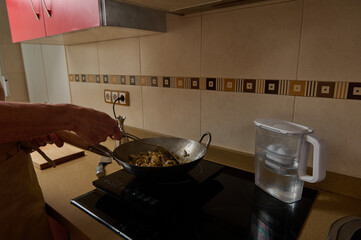 Father Cooking Stir-Fry In Warm Kitchen While Child Helps Prepare Dinner
