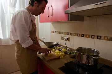 Father Cooking Soup in Kitchen While Child Helps Chop Potatoes and Prep Dinner