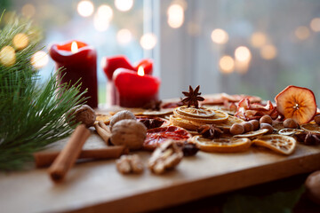 Dried citrus fruits and apple rings with nuts on rustic wood. Background for christmas preparations and decorations.