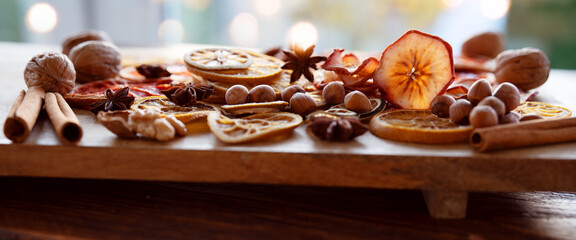 Dried citrus fruits and apple rings with nuts on rustic wood for the christmas. Preparations for christmas hot drinks.