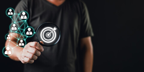 Businessman analyzing target audience with magnifying glass, representing marketing strategy, customer targeting, digital network, and business growth concept for data-driven advertising success.