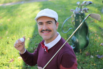 Handsome elegant golfer with a mustache holding a ball