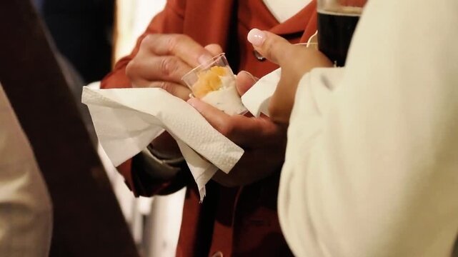 Moment de convivialité entre invités lors d’un mariage, partage d’un amuse-bouche et d’une boisson pendant le vin d’honneur d’une réception élégante.
