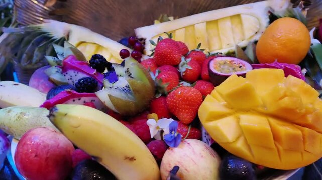 Assortiment de fruits exotiques et de saison &mdash; mangue, fraises, kiwi, ananas, fruit du dragon &mdash; sur un buffet de mariage &eacute;l&eacute;gant et color&eacute;.
