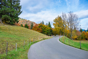 Golden autumn landscape in Saxeten valley near Interlaken West, Switzerland. Scenic mountain view with colorful forest, clear blue sky, and peaceful countryside atmosphere for travel inspiration.