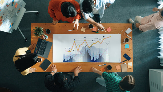 A diverse team collaborates on business data analysis, focusing on graphs and charts in a modern office setting, fostering productivity and ideas. Scalp