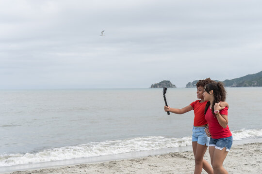 Two teen girls vlogging on beach vacation creating content