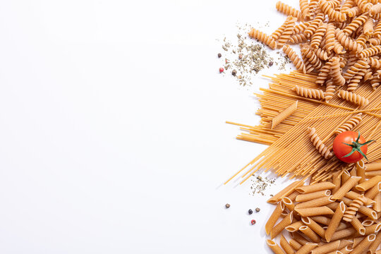 Assorted whole wheat pasta with copy space on white background.