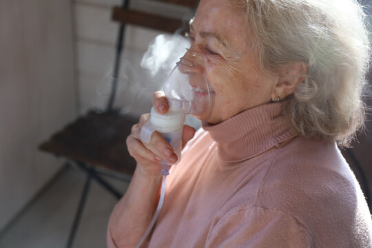 an elderly woman is doing an inhalation and smiling