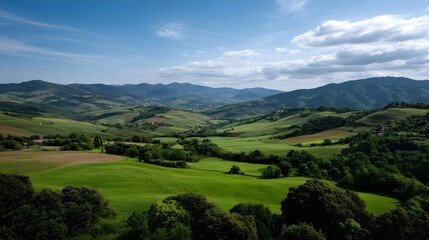 A vast expanse of rolling green hills and valleys under a blue sky with scattered clouds