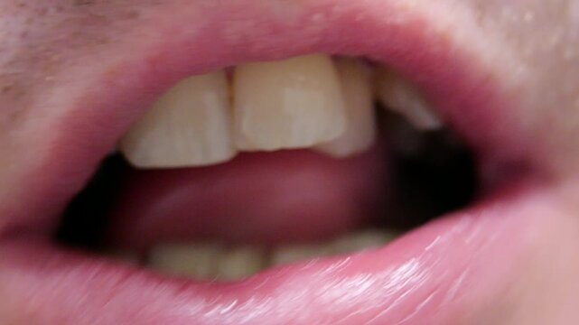 Mouth close up man slowly dissolving throat lozenge moving tongue lightly tapping teeth clear saliva detail oral relief action realistic chewing sounds healthcare symptom soothing warm human intimacy