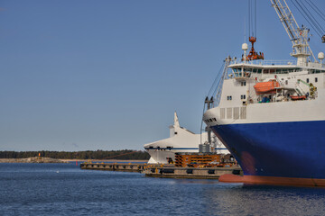 Cargo ship stationed at harbor with cranes overhead and tranquil waters
