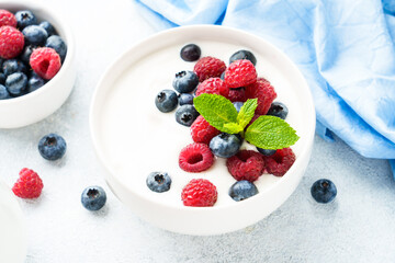Yogurt with fresh berries in white bowl.