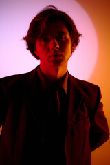 Fototapeta premium Stylish young man poses confidently against a vibrant backdrop of colors and light
