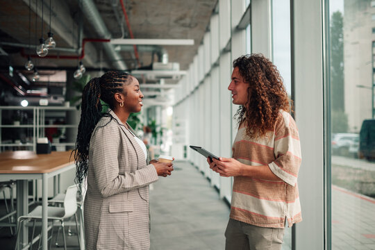 Diverse coworkers collaborating talking holding coffee and tablet