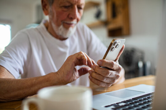 Senior man focused on smartphone at home - Powered by Adobe