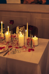Warm candlelit banquet table with roses and crystal decor in restaurant