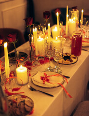 Warm candlelit banquet table with roses and crystal decor in restaurant