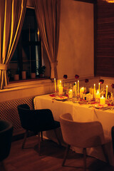 Warm candlelit banquet table with roses and crystal decor in restaurant