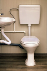 Closed toilet bowl next to a ceramic sink inside small bathroom interior