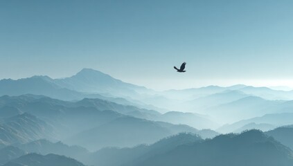 Silhouette of a bird soaring over a mountain range against a hazy sky