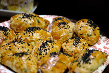 Macro and close-up shot of delicious homemade black cumin pastries. Turkish pastries. Breakfast pastries with cheese and parsley, made by a housewife, on a red plate. Traditional delicacies.