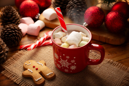 Hot chocolate with marshmallows, a traditional hot drink made for Christmas time and holidays. Served in a red mug and accompanied by gingerbread men cookies.