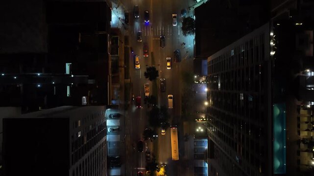 Top down aerial view of traffic flowing through an illuminated city street in Lima, Peru, surrounded by modern buildings and skyscrapers