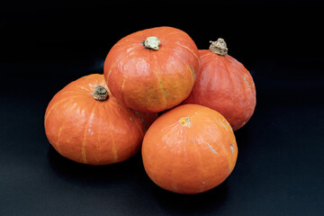 Four ripe orange pumpkins with natural texture arranged on black background. Clean studio shot suitable for food, harvest, market, farm and autumn seasonal concepts.