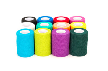 Bright multicolor cohesive bandage rolls arranged in rows on a white studio background. Medical and first-aid elastic wrap supplies displayed neatly for healthcare, veterinary, and sports use.