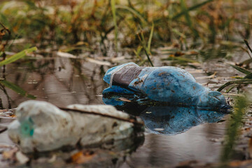 Puste plastikowe butelki wyrzucone do wody © Artur