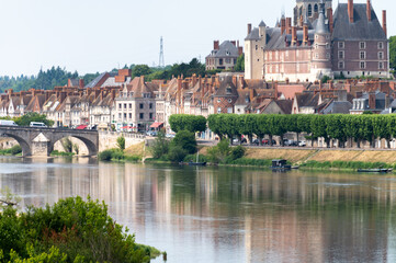 Fototapeta premium Views of old part of town of Gien on the Loire river, in Loiret department, France, houses with tiled roofs and chimneys, castle and bridge