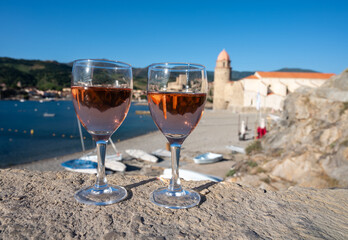 Glasses of rose Collioure AOC wine in sunlights with view on old town Collioure, colorful houses, church, castle and beaches, Occitanie, France, tourists destination