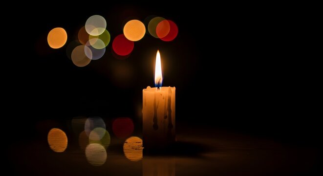 Candle flame light glowing in darkness candlelight blurred background illuminated burn warm faith