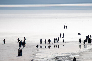 The salt lake in Ankara, Turkey fascinates visitors with its white salt cover. The photo shows many visitors walking on the salt lake.