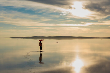 Tuz Lake, located in Ankara province of T&uuml;rkiye, has a wonderful view at sunset. Visitors walking in the shallow waters of the lake watch the sunset by taking photos or taking pictures.