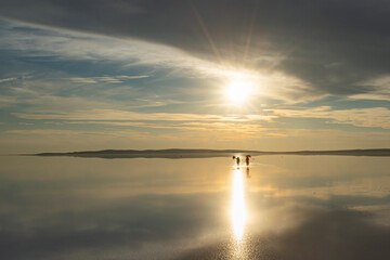Tuz Lake, located in Ankara province of T&uuml;rkiye, has a wonderful view at sunset. Visitors walking in the shallow waters of the lake watch the sunset by taking photos or taking pictures.