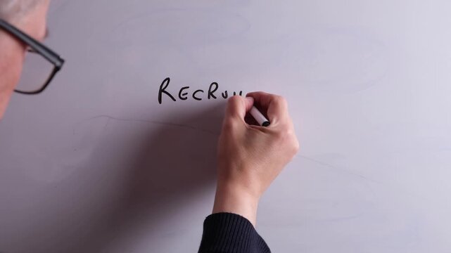 An HR business professional is writing Recruitment Strategy on a whiteboard in black marker pen, ideal for HR, recruitment, and business workplace presentations.
