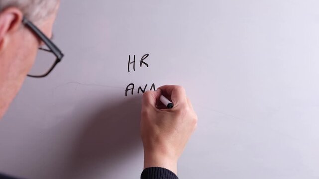 A Human Resources business professional is writing HR Analytics on a whiteboard in black marker pen, ideal for HR, recruitment, and business workplace presentations.
