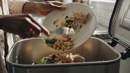 Hands discard leftover meal into kitchen bin, highlighting food waste concerns and sustainable living